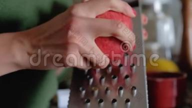 靠近女人的双手，用金属烤架将一个带皮的红苹果烤焦